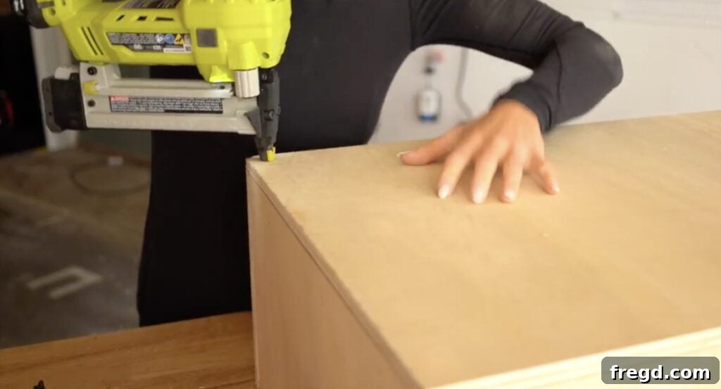 Securely stapling the top plywood panel to the bench frame, completing the structural box before upholstery begins.