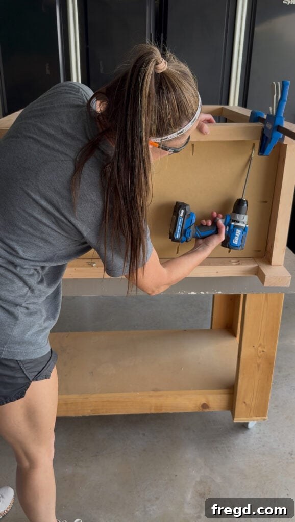 Installing the bottom panel into the cabinet base using pocket hole screws and clamps.