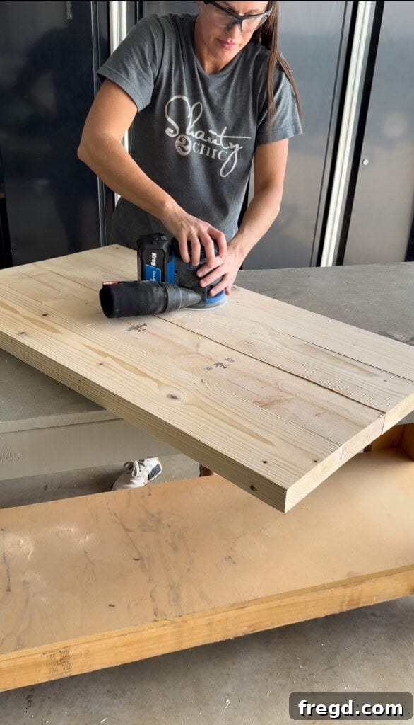 Sanding the cabinet base smooth after filling nail holes, using an orbital sander.