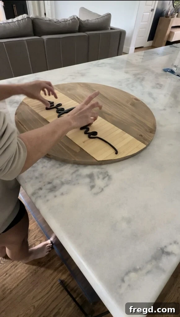 Gluing the painted 'Welcome' lettering onto the wood circle.
