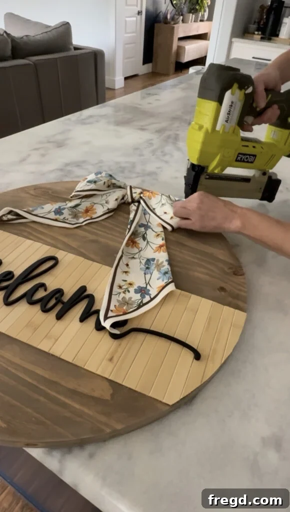 Attaching a decorative scarf as a bow to the top of the door hanger.
