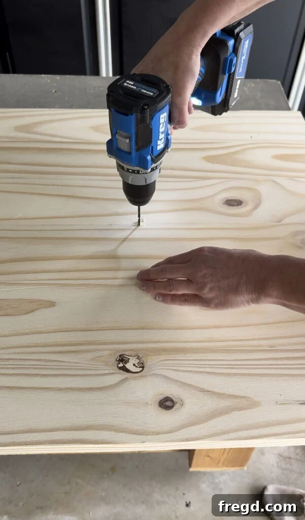 Drilling a small pivot hole in the center of the wood panel.